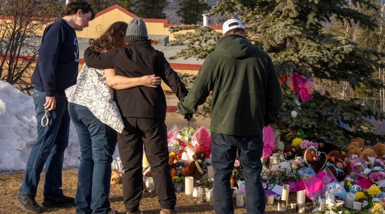 Residents hug as they place flowers at a memorial for the victims of Tuesday's mass shooting in Tumbler Ridge, British Columbia, Canada, on Thursday, Feb. 12, 2026. (Christinne Muschi/The Canadian Press via AP)