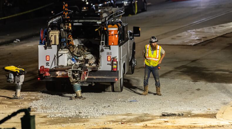 Workers continued to put the finishing touches on the filled in water main hole Wednesday morning, June 5, 2024 following the city’s announcement that water had been restored following the break on West Peachtree Street and 11th Street. The city said the system was being brought back online slowly to “allow system pressures to build.” (John Spink/AJC)