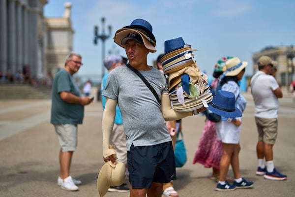 A vendor sells hats during a heat wave in Madrid, Spain, Tuesday, July 1, 2025. (AP Photo/Manu Fernandez)
