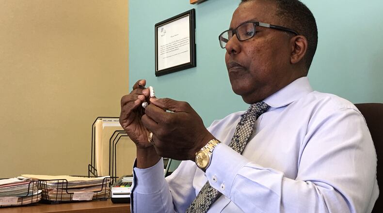 Vic Warmsby cleans a patient’s hearing aid at his Miracle-Ear office in Marietta. Ann Hardie for the AJC
