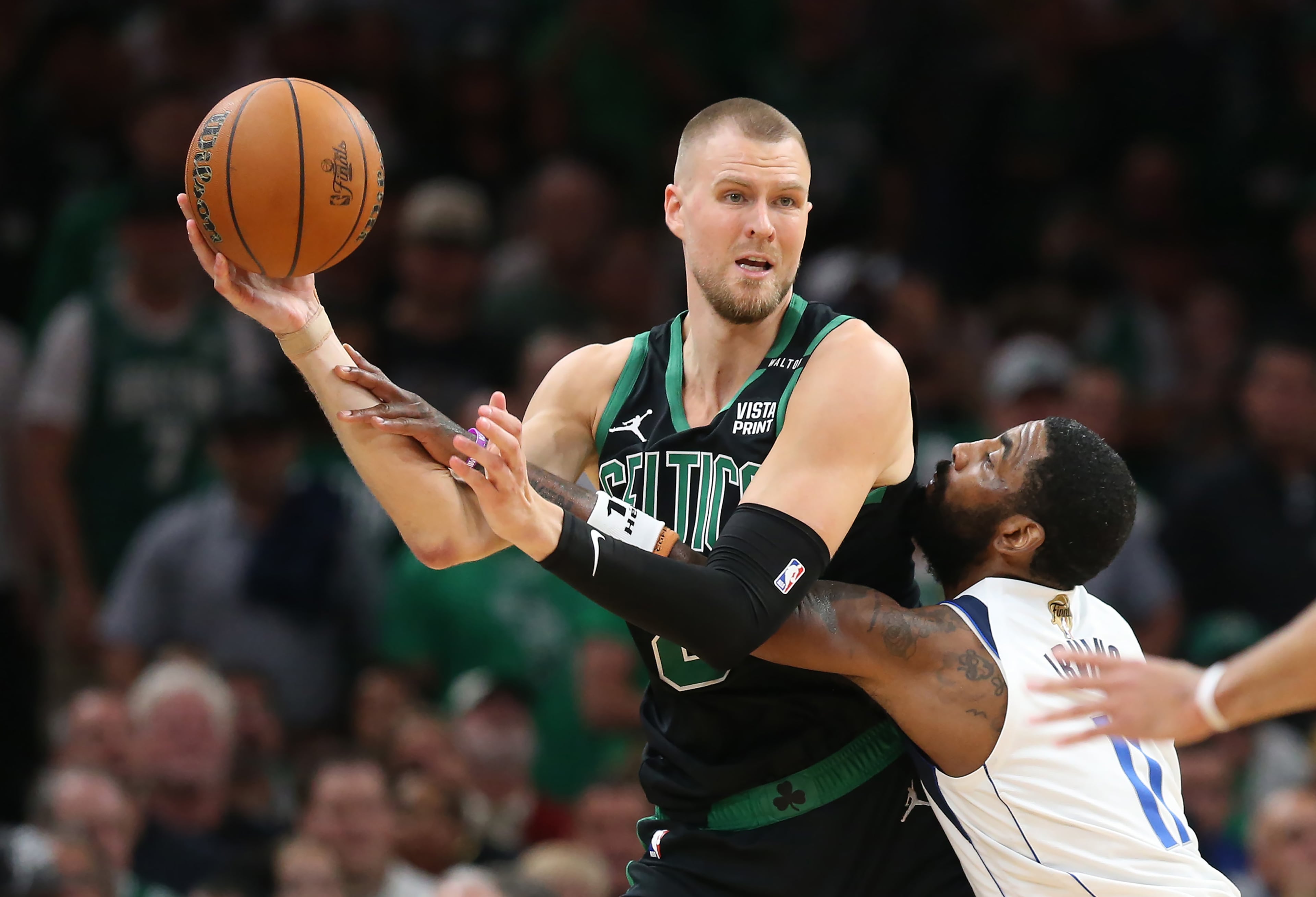 The Celtics' Kristaps Porzingis looks to pass over the Mavericks' Kyrie Irving during Game 2 of the NBA Finals at the TD Garden in Boston on Sunday, June 9, 2024. Tuesday’s trade will bring Porzingis to Atlanta. (Nancy Lane/Boston Herald/TNS)