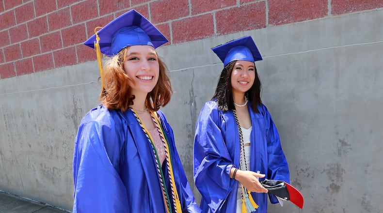 Rachel Rigsbee (left) and Emily Guo (right) walk to their graduation ceremony for Chattahoochee High School on May 21, 2019, at Ameris Bank Amphitheatre in Alpharetta. Guo is heading to Stanford to study the intersection of science, technology and society. Rigsbee will study environmental engineering at Georgia Tech. CURTIS COMPTON / CCOMPTON@AJC.COM