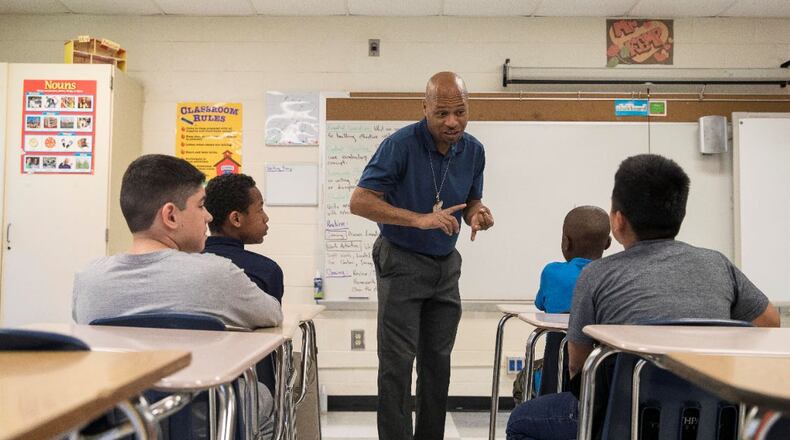 Intensive English teacher Negial Kemo talks with his students at the International Student Center, a DeKalb County School District school in Decatur. (AJC FILE PHOTO)