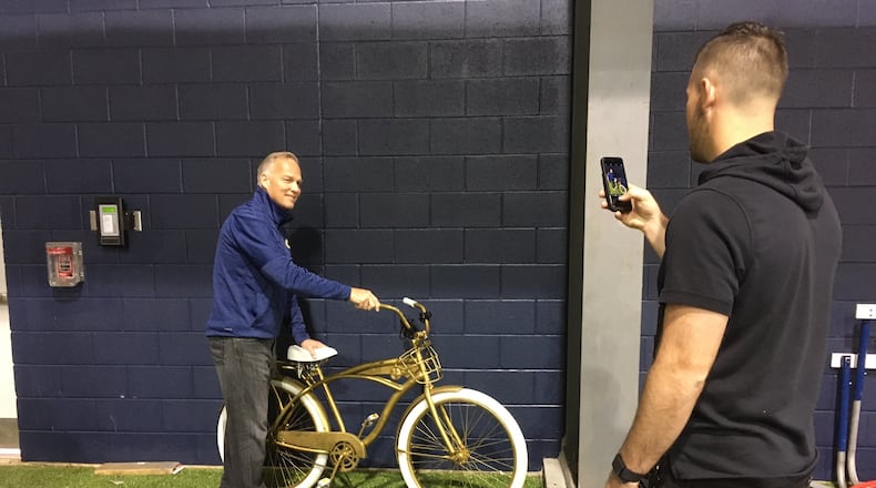 Former Georgia Tech coach Mark Richt poses for a photo with Georgia Tech's "Chaos Cruzer," a bicycle that is awarded to defensive players for their performance at practice. RIcht's son, Jon, is taking the photo at the Brock Football Practice Facility on March 10, 2020. (AJC photo by Ken Sugiura)