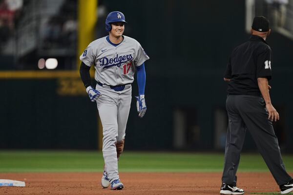 Los Angeles Dodgers' Shohei Ohtani walks to the dugout past umpire Vic Carapazza after a Teoscar Hernandez fly out in the eighth inning of a baseball game against the Texas Rangers in Arlington, Texas, Sunday, April 20, 2025. (AP Photo/Tony Gutierrez)