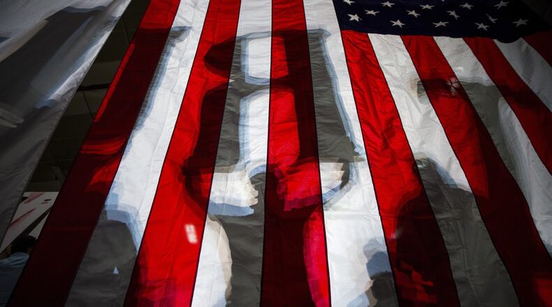 Shadows of Donald Trump supporters, holding up letters to spell his name, show through an American flag at a campaign event for the Republican presidential nominee, at the Travis County Exposition Center in Austin, Texas, Aug. 23, 2016. On Thursday, Hillary Clinton plans to delivered a major address denouncing Trump’s embrace of the “alt-right” political philosophy, presenting his choice as an especially ominous turn in a presidential election full of them. (Damon Winter/The New York Times)