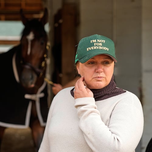 Trainer Cherie DeVaux stands watches from a barn after a workout at Churchill Downs Monday, April 27, 2026, in Louisville, Ky. (AP Photo/Charlie Riedel)