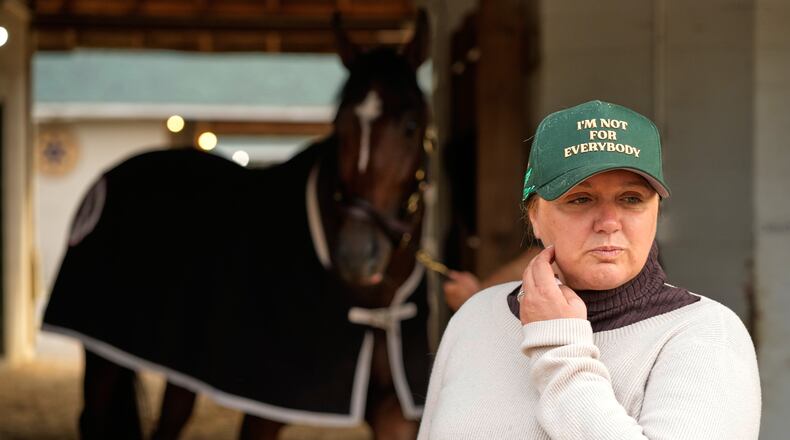 Trainer Cherie DeVaux stands watches from a barn after a workout at Churchill Downs Monday, April 27, 2026, in Louisville, Ky. (AP Photo/Charlie Riedel)