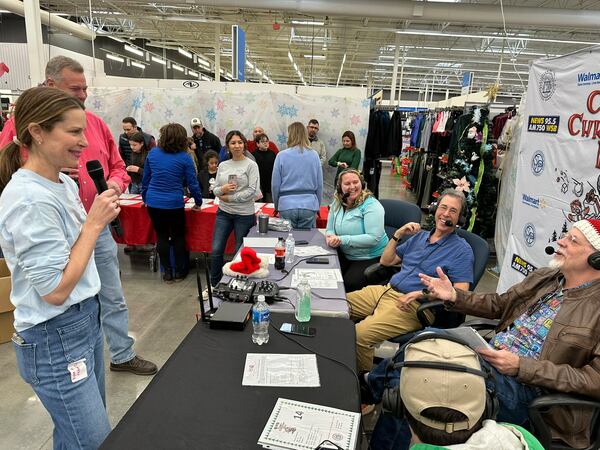 Clark Howard's wife, Lane (left), banters with him live on WSB radio Dec. 8 at the Roswell Walmart for Clark's Christmas Kids. Eric Von Haessler, a WSB afternoon host, is speaking on the far right. Rodney Ho/AJC