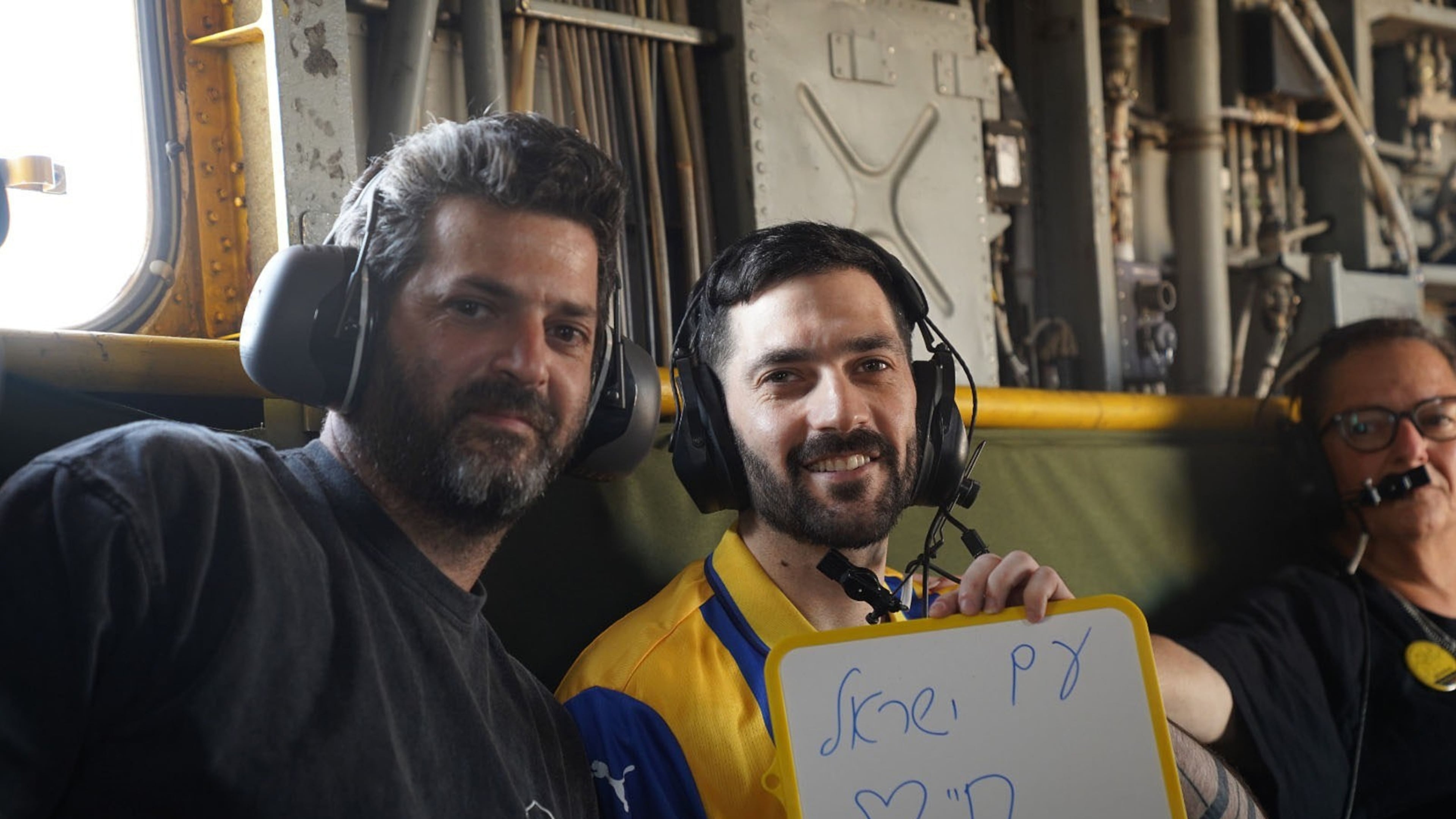 Gali Berman, carries a placard reading in Hebrew "The People of Israel Live," as he sits onboard an IAF helicopter en route to the hospital after being released from Hamas captivity, on Monday, Oct. 13, 2025. (IDF via AP)