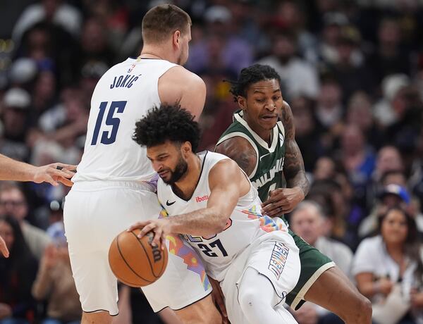 Milwaukee Bucks guard Kevin Porter Jr., back right, is blocked by Denver Nuggets center Nikola Jokic, back left, as guard Jamal Murray heads to the basket in the first half of an NBA basketball game Wednesday, March 26, 2025, in Denver. (AP Photo/David Zalubowski)