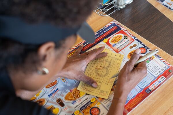 Shanell Collins tallies a customer’s bill by hand at the Waffle House on Peachtree Road in Brookhaven on Friday, Aug. 14, 2026. Although the cash register is electronic, Waffle House still gives customers hand-written checks. (Ben Gray for the AJC)