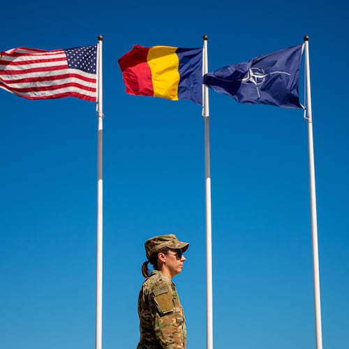 U.S. Staff Sergeant Alyssa Blom walks by flags at the Mihail Kogalniceanu Air Base, in Mihail Kogalniceanu, Romania, Thursday, Sept. 10, 2026. (AP Photo/Andreea Alexandru)