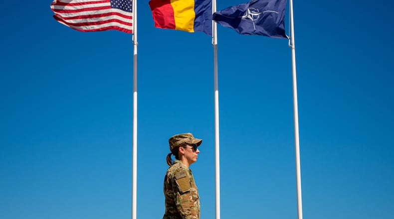 U.S. Staff Sergeant Alyssa Blom walks by flags at the Mihail Kogalniceanu Air Base, in Mihail Kogalniceanu, Romania, Thursday, Sept. 10, 2026. (AP Photo/Andreea Alexandru)