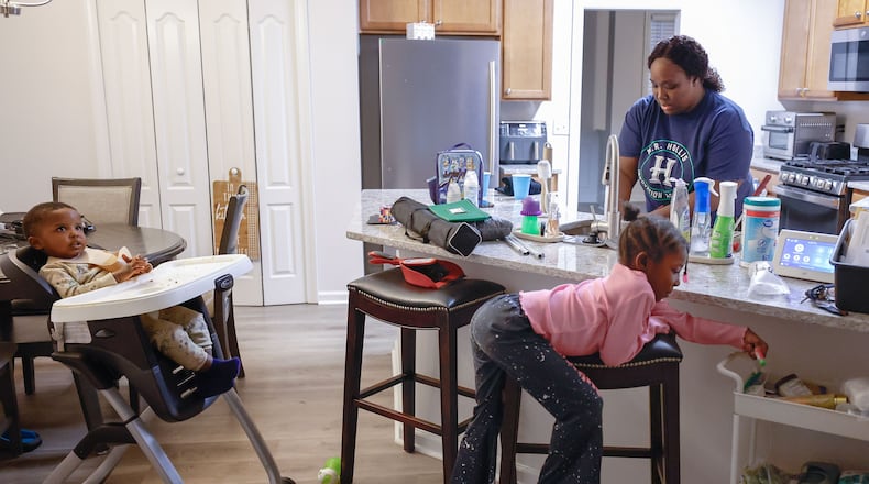 Shanyce Smith washes dishes alongside her children Legend, 2, and Legacy, 5, at her home in Douglasville on Thursday, Feb. 27, 2025. After receiving a scholarship for child care, Smith and her husband were able to save enough money to buy a new home and now have more free time to spend with their children instead of working multiple jobs to cover child care expenses. (Natrice Miller/ AJC)