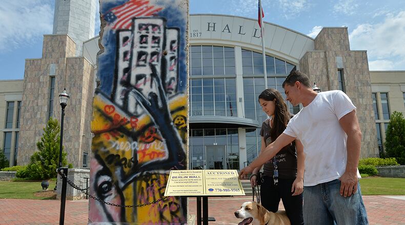 Dianne Meuse and her friend, Adam Pietroski, both of Buford, check out a 12-foot-tall section of the Berlin Wall on display in front of Suwanee City Hall.