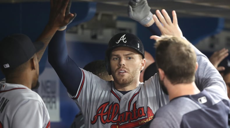 Freddie Freeman of the Atlanta Braves is congratulated by teammates in the dugout after hitting a two-run home run in the fifth inning against the Toronto Blue Jays Tuesday. (Photo by Tom Szczerbowski/Getty Images)
