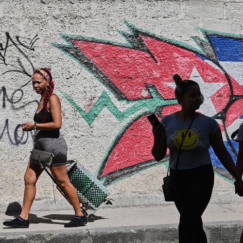 People walk past graffiti in the colors of the Cuban flag in Havana, Cuba, Wednesday, June 17, 2026. (AP Photo/Jorge Luis Banos)