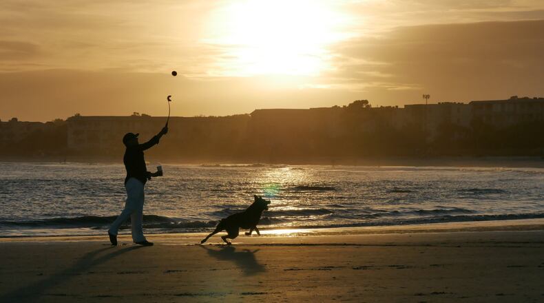 A beachgoer plays with his dog on the beach in St. Simons Island, whose the easygoing seaside lifestyle has drawn many Atlanta retirees. HYOSUB SHIN / HSHIN@AJC.COM