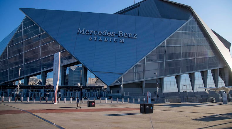 One person walks past Mercedes-Benz Stadium, which would have been the site of the college basketball Final Four this weekend. It was cancelled due to the coronavirus outbreak. (ALYSSA POINTER / ALYSSA.POINTER@AJC.COM)