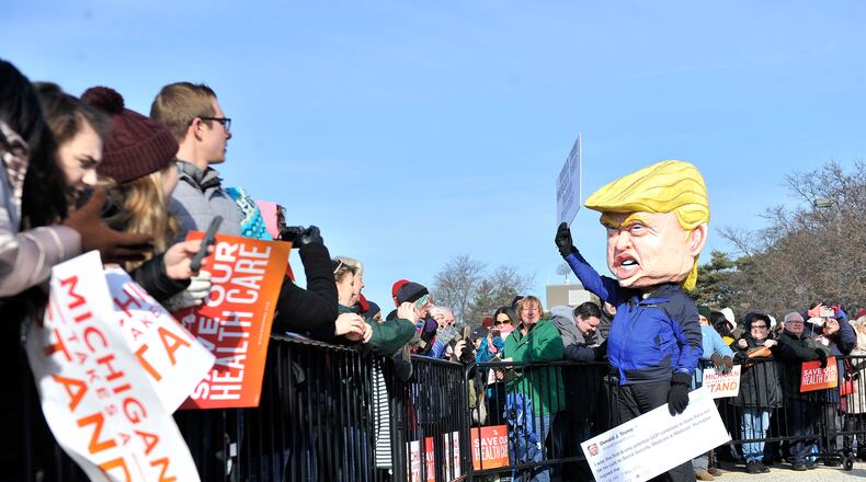 In a Sunday, Jan. 15, 2017 photo, A person dressed as Donald Trump waves before a rally for health care at Macomb Community College in Warren, Mich. Thousands of people showed up in freezing temperatures on Sunday in Michigan to hear Sanders denounce Republican efforts to repeal President Barack Obama's health care law, one of dozens of rallies Democrats staged across the country to highlight opposition. (Robin Buckson/The Detroit News via AP)