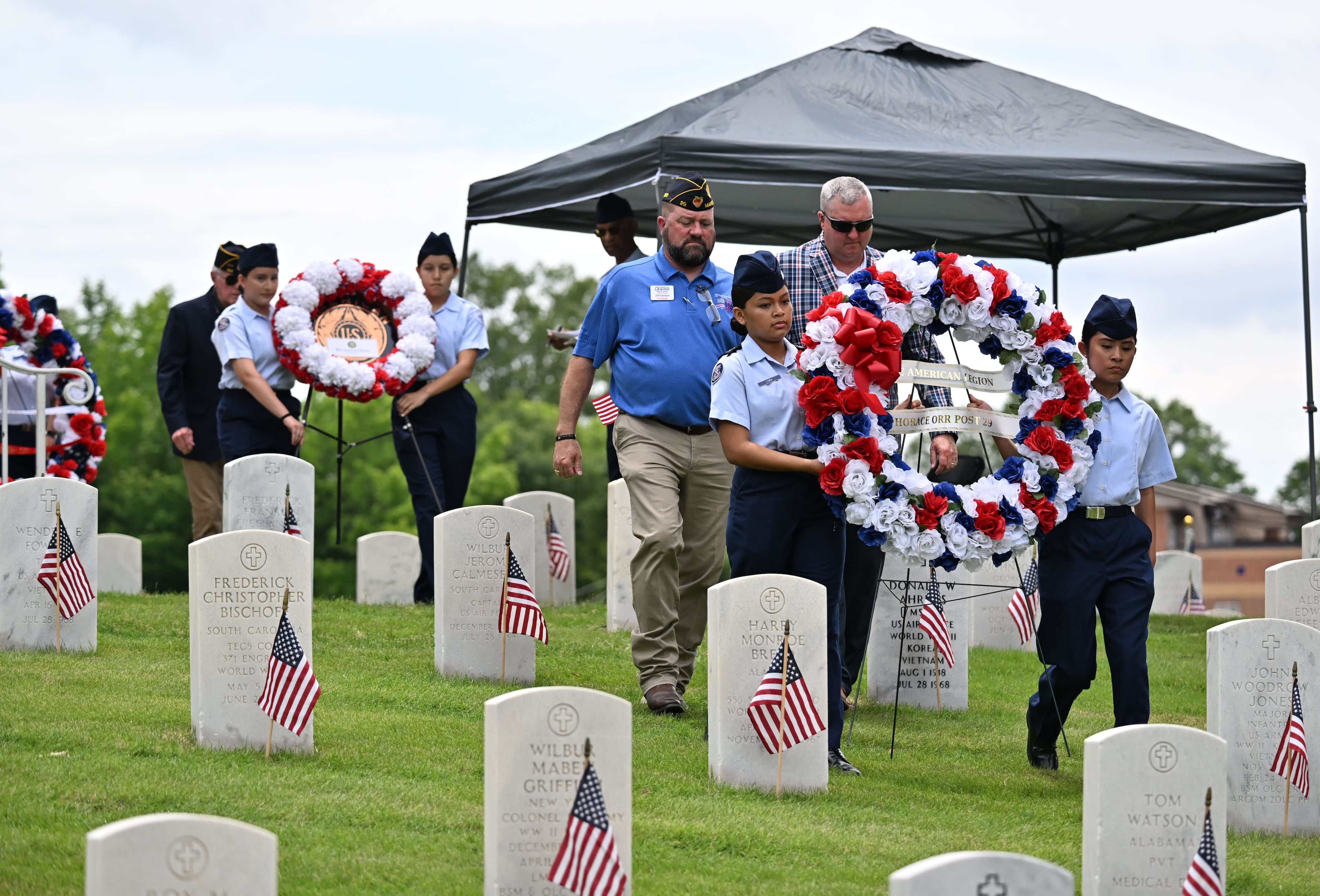 Marietta High School Air Force JROTC members escort the Memorial Wreath Presenters as they present the floral wreaths during the Memorial Day ceremony at Marietta National Cemetery, Monday, May 26, 2025, in Marietta. (Hyosub Shin / AJC)