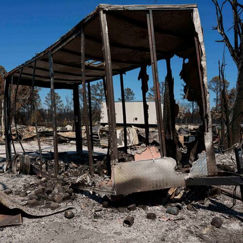 A burned trailer sits near a destroyed home as the Brantley Highway 82 fire burns, Thursday, April 23, 2026, near Nahunta, Ga. (AP Photo/Mike Stewart)
