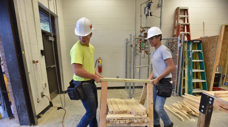 Michael Lyons (left), 16, and Marvin Rodas, 17, carry components as they build book exchanges at Maxwell High School of Technology on Tuesday, Oct. 15, 2019. Students are partnering with Gwinnett Coalition in the GREAT (Gwinnett Reading Exchange & Art Transforms) Little Minds initiative to provide access to books and encourage art appreciation. The student artists were building book exchanges at the school. HYOSUB SHIN / HYOSUB.SHIN@AJC.COM