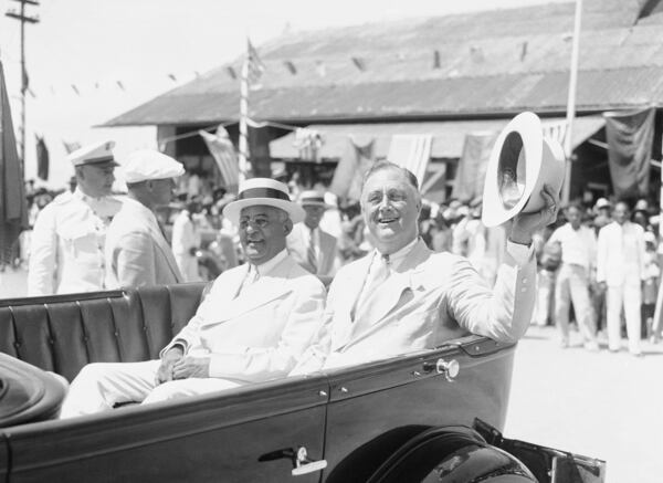 President Franklin D. Roosevelt lifts his hat in acknowledgement of the cheers of people in Cape Haitien, Haiti, who gathered to greet him on his arrival for an exchange of visits with President Sternio Vincent of Haiti, July 8, 1934. (AP Photo)