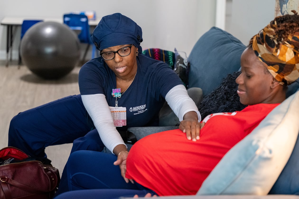 Doula Bashellia Williams (left) checks the position of her client, Reona Porter’s baby at Porter’s Stockbridge apartment on Friday, Oct. 8, 2024. Porter was just over 38 weeks pregnant. (Bita Honarvar for the AJC)