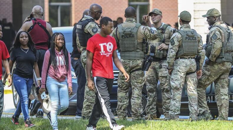 Stephenson High School students walk past DeKalb County SWAT officers outside the school Tuesday morning, Aug. 13, 2019. Officers burst into classrooms with guns drawn after a student reported seeing an armed classmate. The gun scare prompted a heavy police presence, road closures and a Level 3 lockdown at the school on Stephenson Road in Stone Mountain. JOHN SPINK/JSPINK@AJC.COM