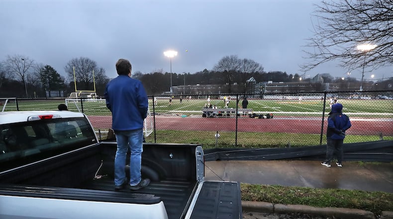 John MaCauley (left) has to watch his daughter Gretchen “The Gretch” McCauley compete in her girl’s soccer game from the public sidewalk outside the fence on Chester Avenue at Maynard Jackson High School on Feb. 18, 2021, in Atlanta. Atlanta Public Schools isn’t currently allowing parents or any spectators to watch athletic events in-person because of COVID-19. (Curtis Compton / Curtis.Compton@ajc.com_