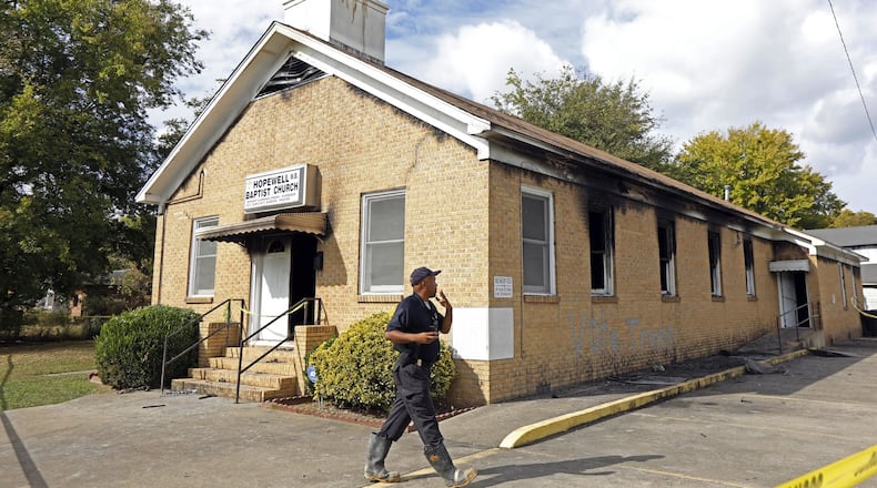 A state fire marshal investigates the fire damaged Hopewell M.B. Baptist Church in Greenville, Miss., Wednesday, Nov. 2, 2016. “Vote Trump” was spray-painted on an outside wall of the black member church. Fire Chief Ruben Brown tells The Associated Press that firefighters found flames and smoke pouring from the sanctuary of the church just after 9 p.m. Tuesday. (AP Photo/Rogelio V. Solis)