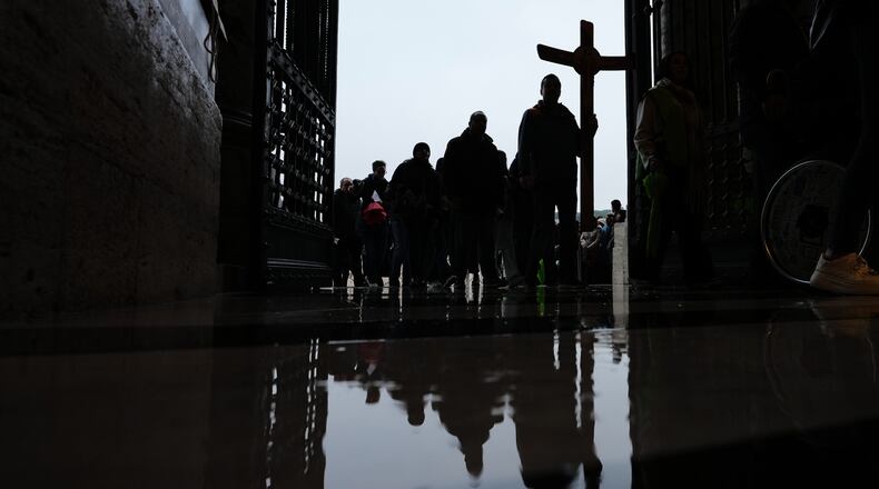Pilgrims and faithful hold a crucifix as they arrive to St. Peter's Basilica at the Vatican to cross the Holy Door on the last day of its public opening, Monday, Jan. 5, 2026. (AP Photo/Alessandra Tarantino)