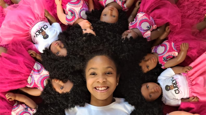 Zoe Oli, 8, surrounded by several of her dolls, is CEO of Beautiful Curly Me. Courtesy of Evana Oli
