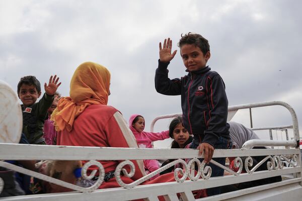 Syrian Bedouin families gesture as they ride in a convoy led by Red Crescent vehicles in Busra al-Harir, heading to Daraa after being evacuated from Sweida following more than a week of violent clashes, Monday, July 21, 2025. (AP Photo/Malek Khattab)