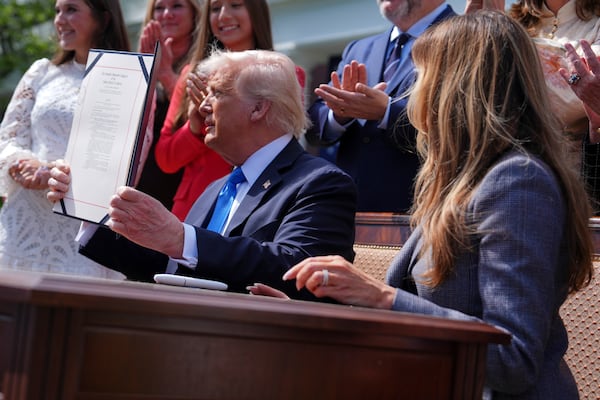 President Donald Trump holds up a bill for the "Take it Down Act" that he and first lady Melania Trump, right, signed in the Rose Garden of the White House, Monday, May 19, 2025, in Washington. (AP Photo/Evan Vucci)