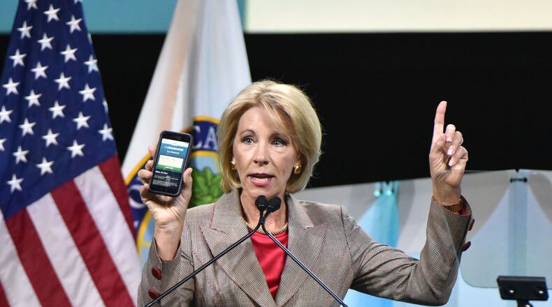 U.S. Education Secretary Betsy DeVos shows FAFSA mobile app as she speaks during 2018 FSA Training Conference at Georgia World Congress Center in Atlanta in November 2018. DeVos announced Wednesday her department is temporarily suspending loan collections for default borrowers. HYOSUB SHIN / HSHIN@AJC.COM