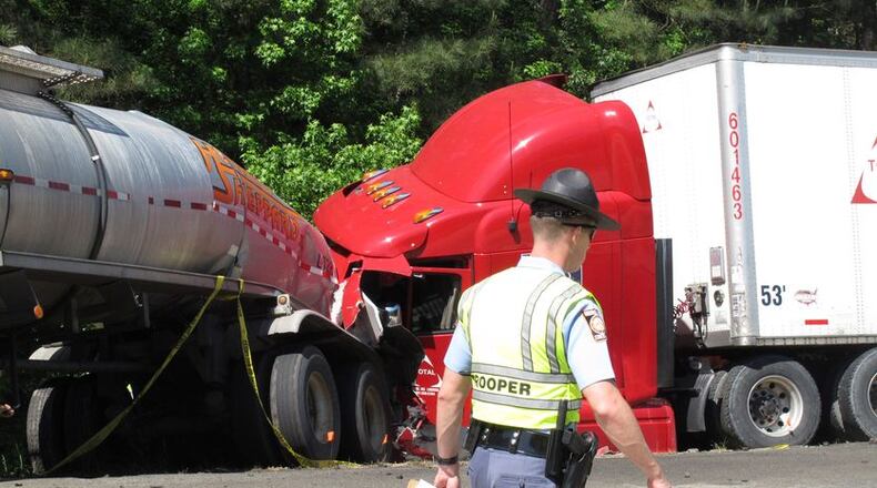 A Georgia state trooper works the scene of a deadly crash in which five people died and three others were injured Wednesday April 22, 2015, in Ellabelle, Ga., west of Savannah. The Georgia State Patrol said seven total vehicles, including two tractor trailers, were involved in the early morning collision on Interstate 16 about 20 miles west of Savannah. (AP Photo/Russ Bynum)