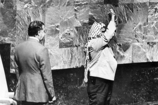 FILE - A holster protrudes from under Yasser Arafat's jacket as he clasps his hands over his head during his appearance before the United Nations General Assembly at the U.N. headquarters, Nov. 13, 1974. (AP Photo, File)