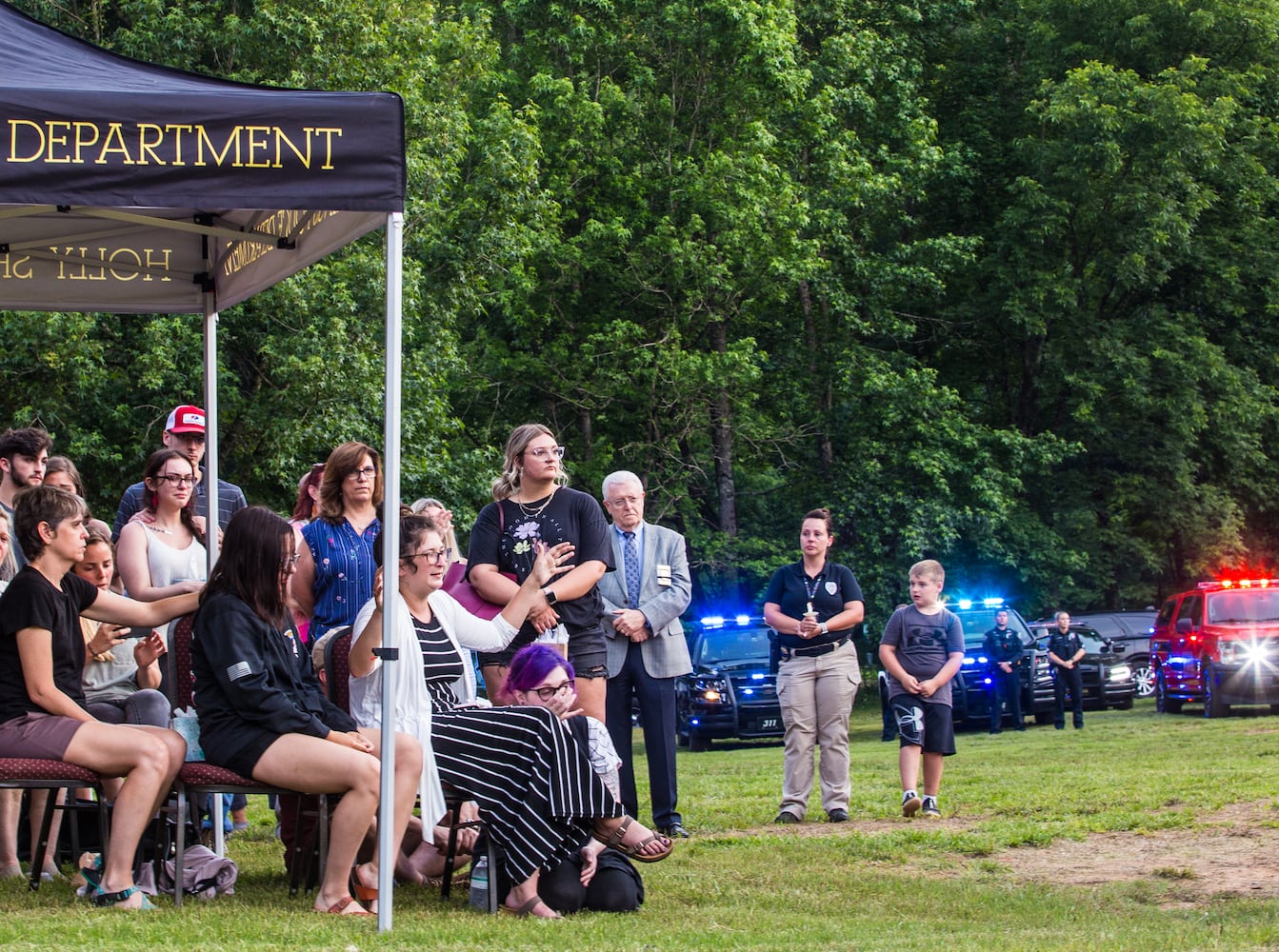 Burson family members, including the wife of fallen officer Joe Burson, Marykate Burson, center in white sweater, as well as the Holly Springs community and neighboring police departments gather at Barrett Park for a candlelight vigil for Holly Springs Police Officer Joe Burson on Friday, June 18, 2021 after he was killed during a traffic stop earlier this week.  The church the Burson family attends led the service with prayer and music.  (Jenni Girtman for The Atlanta Journal-Constitution)