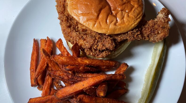 Iron Hill offers a fried chicken sandwich with bread and butter pickles and sriracha ranch dressing on a potato bun, plus sweet potato fries. Bob Townsend for The Atlanta Journal-Constitution