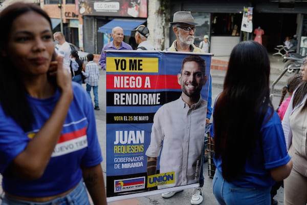 A man holds a banner of Juan Requesens, a candidate for governor of Miranda state in the upcoming regional elections, in Los Teques, Miranda, Venezuela, Thursday, May 15, 2025. (AP Photo/Cristian Hernandez)