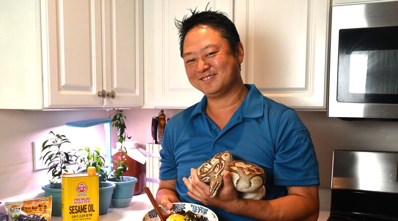 Umi Executive Chef Todd Dae Kulper is seen in his home kitchen with a bowl of bibimbap and his pet python, Zeus. Chris Hunt for The Atlanta Journal-Constitution