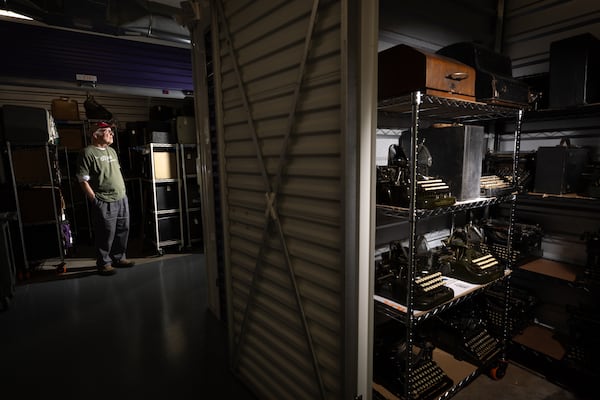Tom Rehkopf poses with two open units of his typewriter collection at a public storage facility in Roswell on November 9, 2025. Rehkopf has collected around 1,000 typewriters. (Arvin Temkar / AJC)