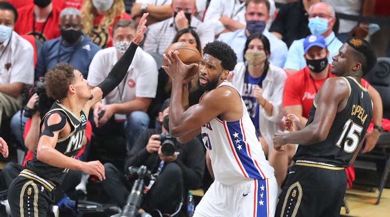Joel Embiid grabs a rebound against Trae Young and Clint Capela during the first half of Monday's Game 4 of the Eastern Conference semifinals.
