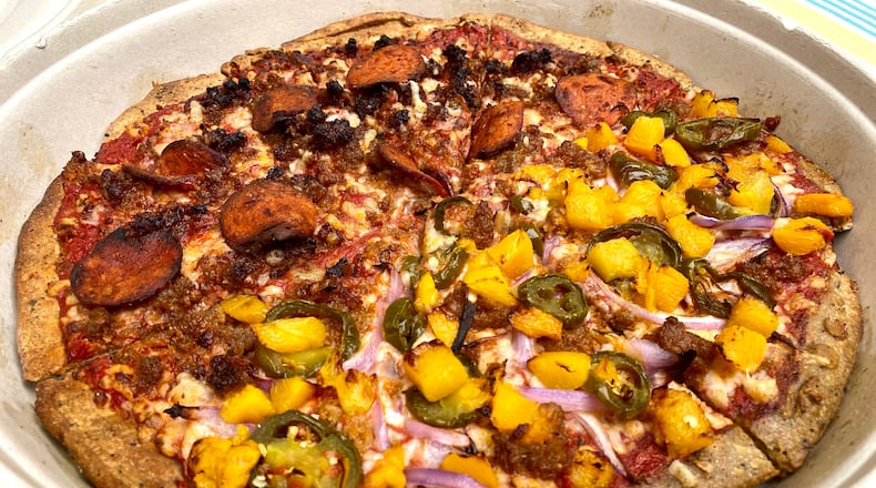 This pizza from Plant-Based Pizzeria & More has one half covered in Vegan Meat Lover's toppings (left), the other with Georgia Peach toppings. Ligaya Figueras/ligaya.figueras@ajc.com