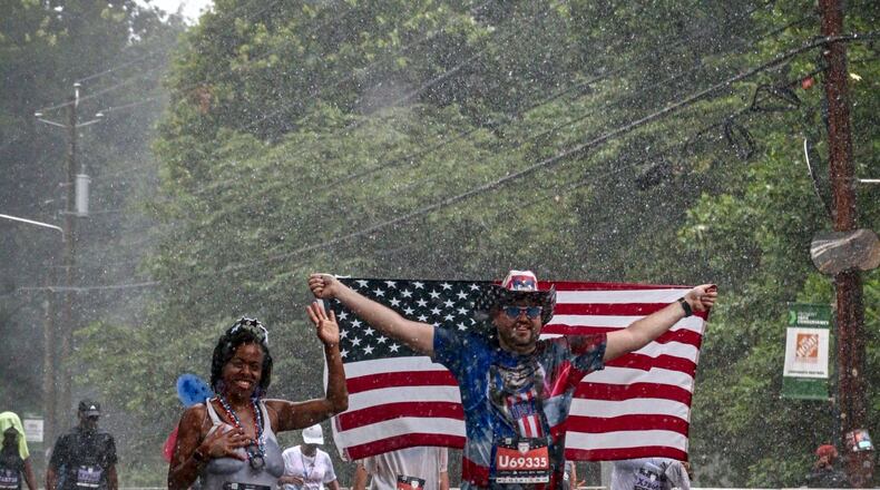 Mark Gorman continued walking in the rain during the Peachtree Road Race Tuesday.
