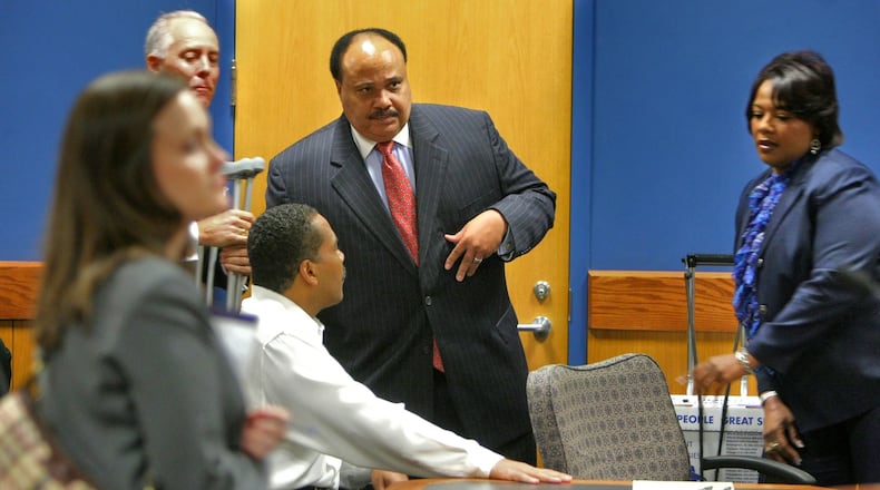 Dexter King (left-seated) greets Martin Luther King III (center) as sister, Bernice King looks on.