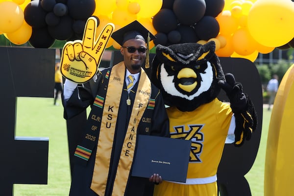 Kennesaw State student Marvin Nyangi poses for a photograph with school mascot Scrappy following spring commencement in May 2025. (Jason Getz/AJC)